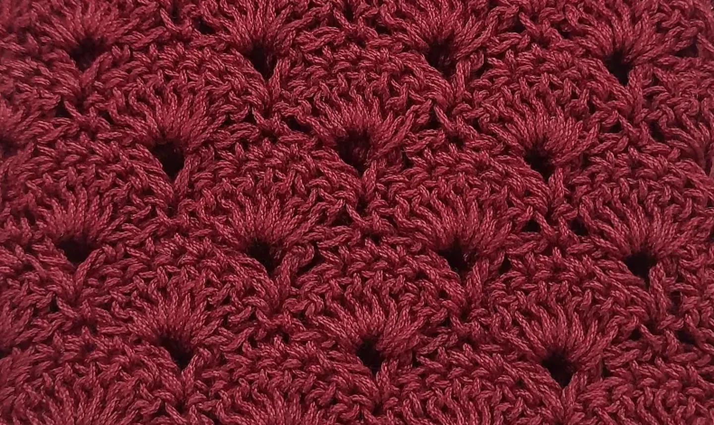 A close view of her shell stitch worked in deep maroon yarn.
