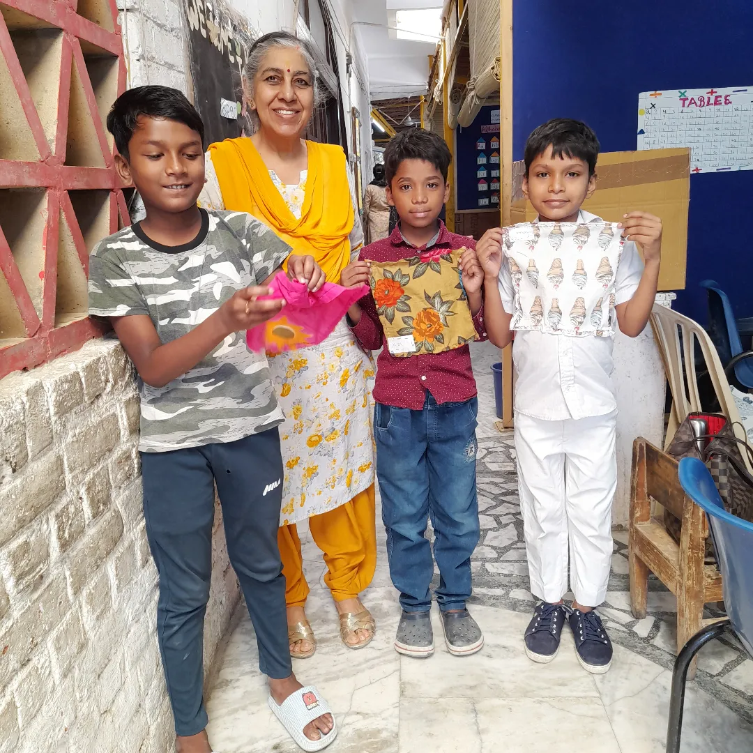 Shikha with three children at Nai Disha, each holding a small pouch she made.