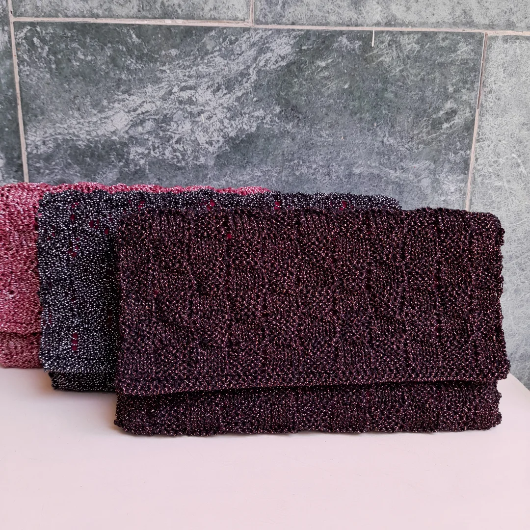 Three folded clutches in maroon, pink and black, their surfaces worked with beads.